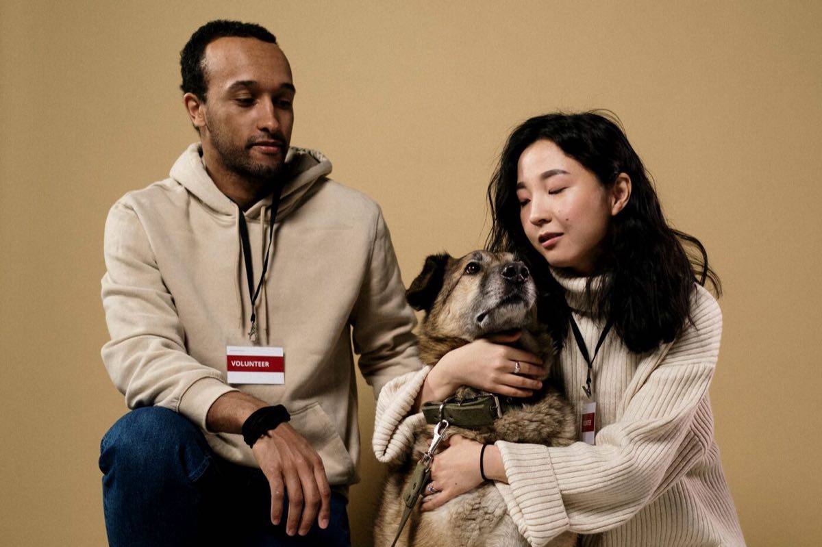 Two people sitting together at home with a dog resting between them.